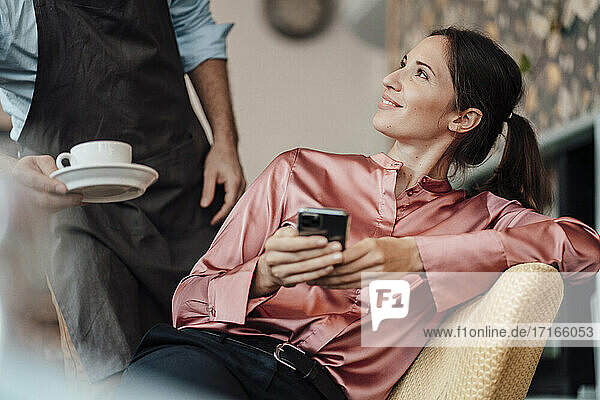 Lächelnde Geschäftsfrau mit Blick auf den männlichen Besitzer eines Cafés