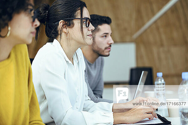 Weibliche und männliche Unternehmer sitzen im Sitzungssaal während einer Besprechung im Büro