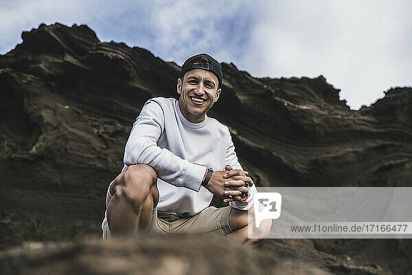 Lächelnder männlicher Tourist auf einem Felsen in El golfo  Lanzarote  Spanien