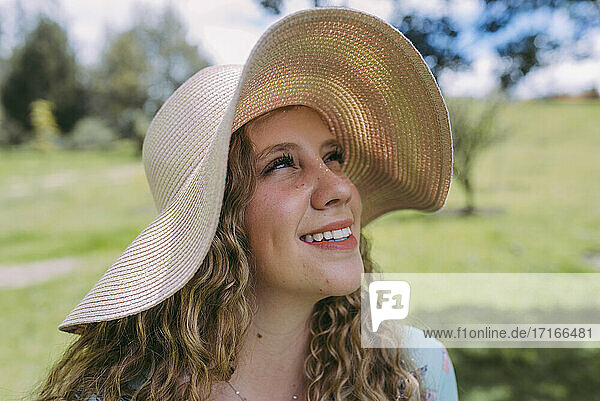 Thoughtful young woman with sun hat during sunny day in park