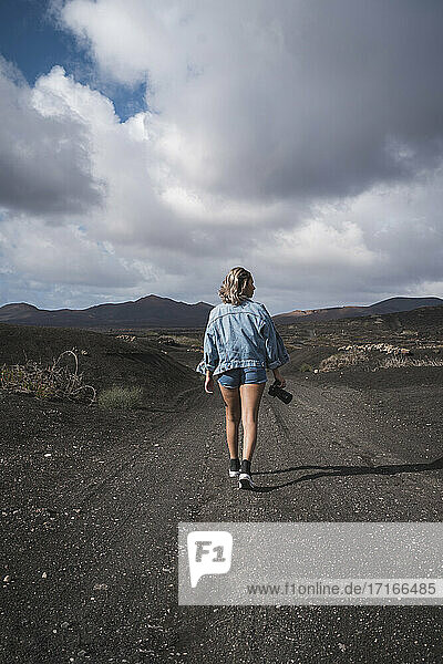 Tourist mit Kamera in der Hand auf dem Fußweg am Vulkan El Cuervo  Lanzarote  Spanien