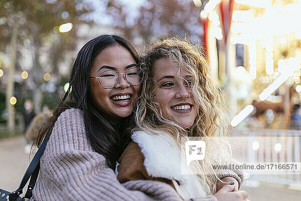 Cheerful female friends embracing at amusement park