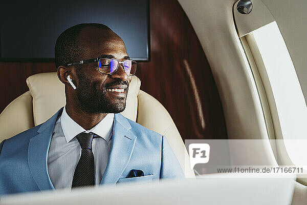 Smiling male entrepreneur with eyes closed in airplane