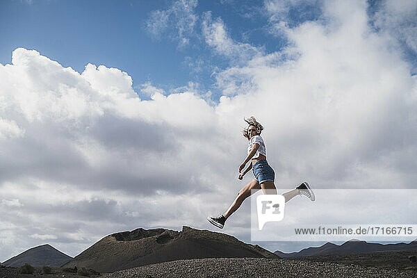 Junge Frau läuft gegen den Himmel am Vulkan El Cuervo  Lanzarote  Spanien