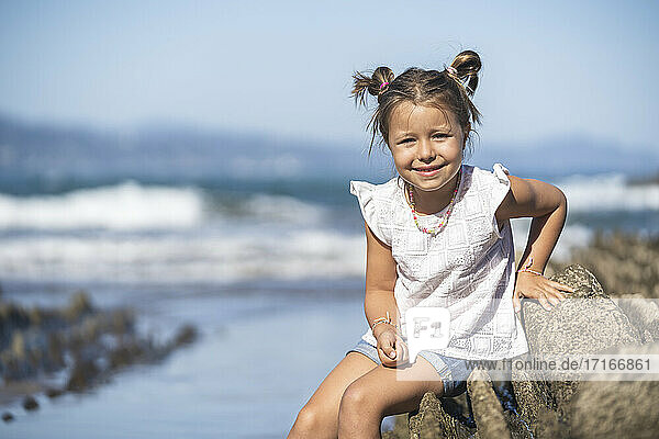 Cute smiling girl sitting on flysch during sunny day