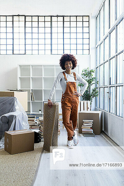 Afro-Frau mit Hand auf der Hüfte  stehend am Teppich in neuer Wohnung