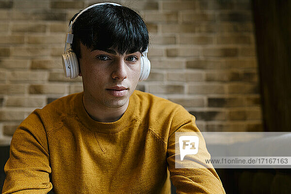 Young man wearing headphones staring while sitting at cafe