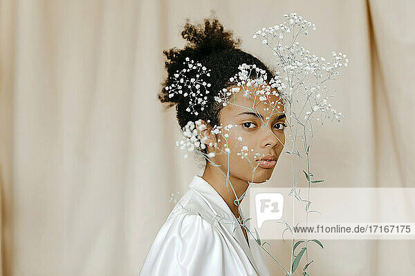 Junge Frau mit weißen Blumen vor dem Gesicht