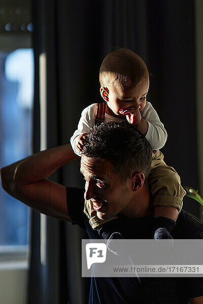Father carrying baby boy while playing at home
