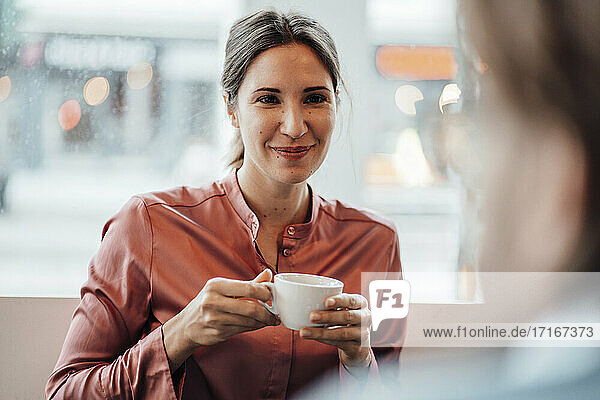 Eine Frau trinkt Kaffee und diskutiert mit einem männlichen Kollegen in einem Café
