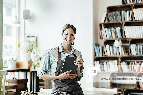 Smiling female cafe owner with digital tablet at coffee shop