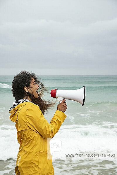 Woman screaming in megaphone while standing at beach