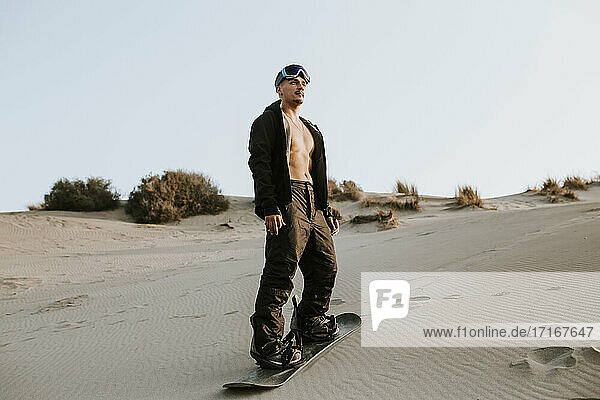 Junger Mann trägt ein Sandboard und steht auf Sand in Almeria  Tabernas-Wüste  Spanien