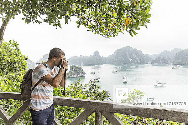 Männlicher Tourist mit Rucksack beim Fotografieren der Halong-Bucht in Vietnam
