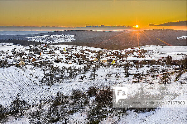 Drone view of snow-covered village at winter sunset