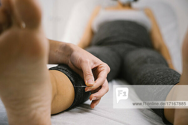 Pregnant woman receiving acupuncture treatment by midwife at hospital