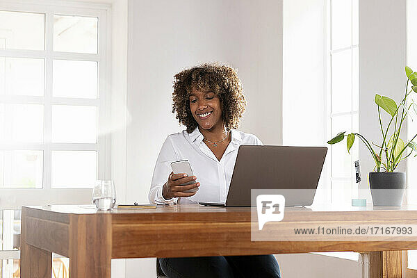 Unternehmer mit Laptop und Mobiltelefon im Home Office sitzend