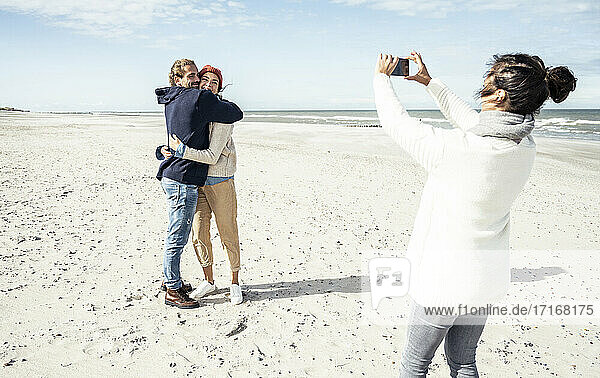 Eine Gruppe von Freunden macht Smartphone-Fotos am Sandstrand