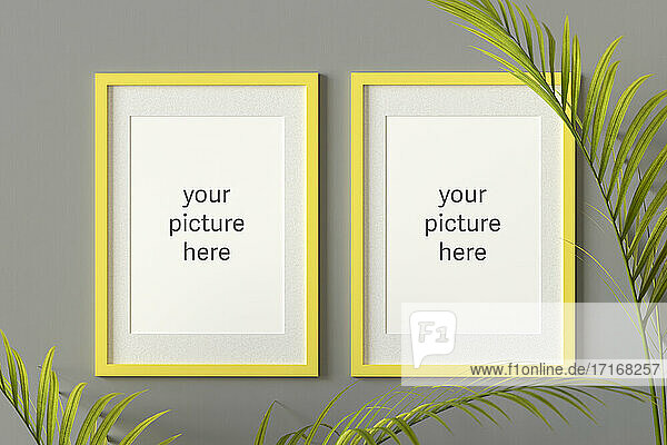 Three dimensional render of two picture frames with placeholder text hanging on gray wall