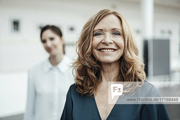 Smiling senior woman with female colleague in background at office