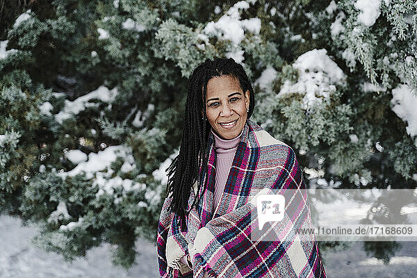 In einen Schal gehüllte hispanische Frau im Winter im Park