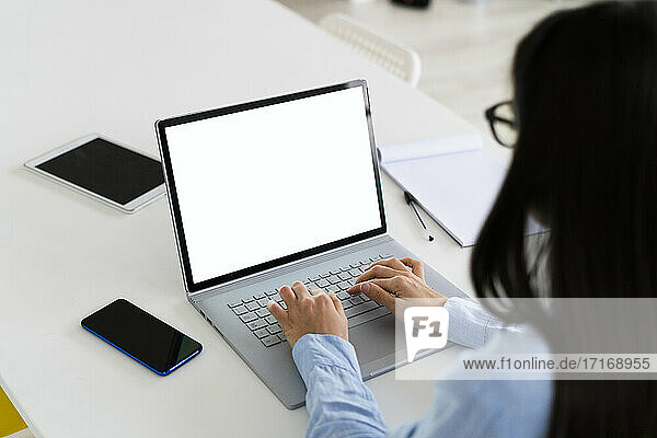 Businesswoman using laptop while working at office