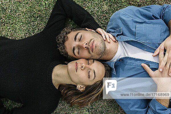 Lächelndes Paar auf dem Rasen liegend mit geschlossenen Augen