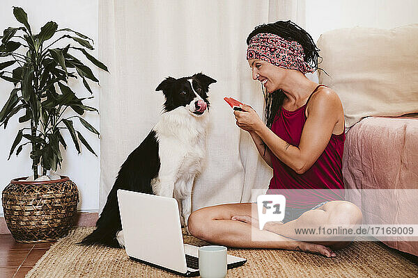 Frau füttert Haustier mit Wassermelone  während sie zu Hause am Laptop sitzt