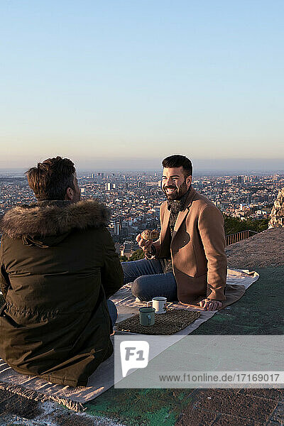Gay couple talking while having breakfast on observation point  Bunkers del Carmel  Barcelona  Spain