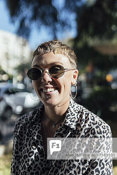 Lächelnde Frau mit Sonnenbrille  die im Freien steht