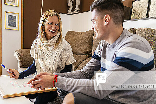 Smiling female therapist with slate advising young patient during session at work place
