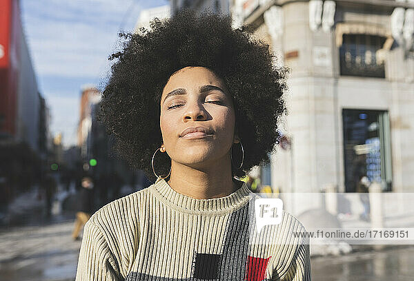 Afro woman with eyes closed standing in city