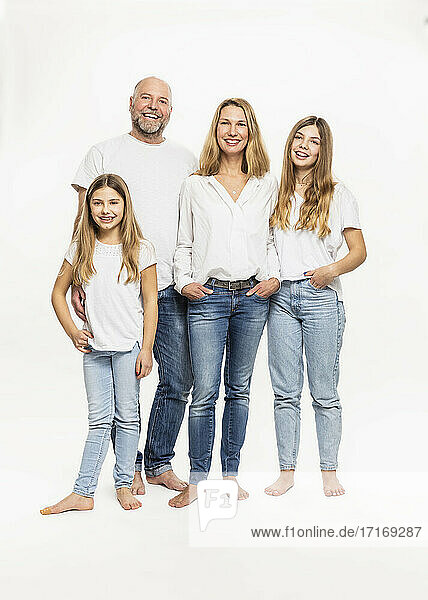 Smiling mother and father with daughters against white background