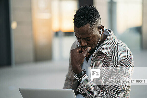 Mann benutzt Laptop und hört Musik