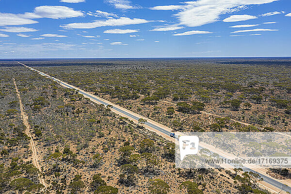 Aerial view of Eyre Highway stretching across Nullarbor National Park with clear line of horizon in background