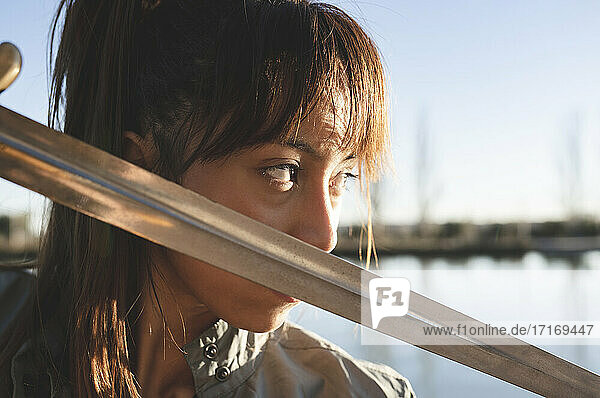 Weibliche Athletin mit intensivem Blick hält Schwert gegen ihr Gesicht an einem sonnigen Tag