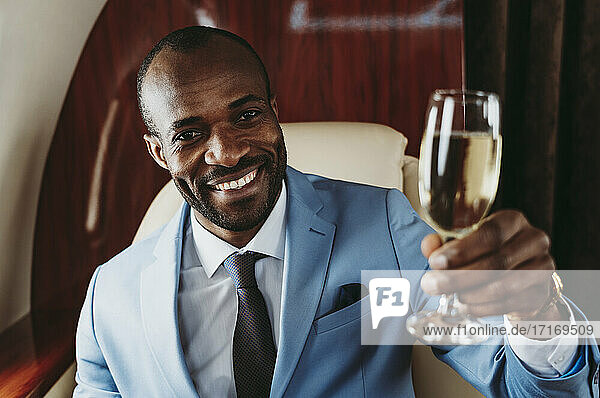 Elegant businessman with champagne traveling in airplane