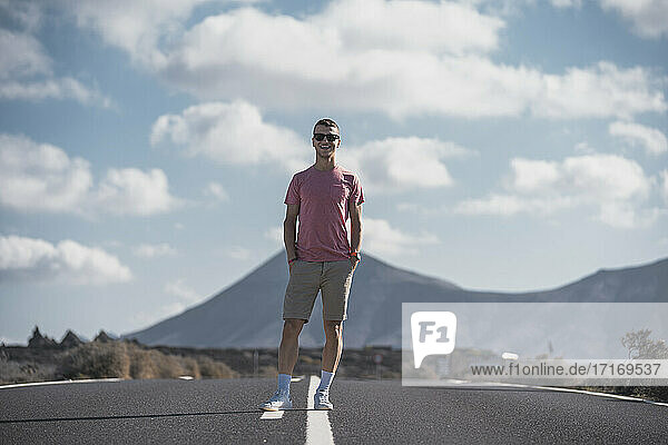 Smiling male tourist with hands in pockets standing on road at Lanzarote  Spain