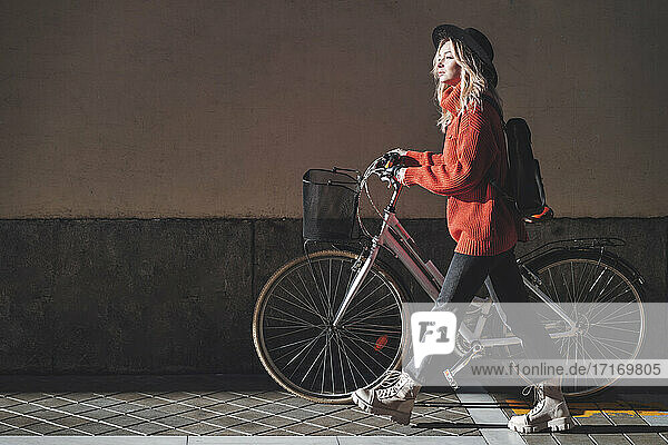Frau mit Hut schaut weg  während sie mit dem Fahrrad gegen die Wand fährt