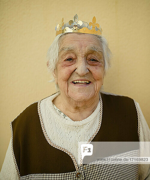 Nahaufnahme einer lächelnden älteren Frau mit Papierkrone