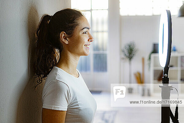 Young woman smiling while looking through circular strobe standing at home
