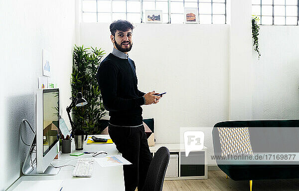 Porträt eines Geschäftsmannes mit Smartphone am Schreibtisch im Büro