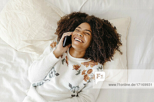 Junge Frau lächelt  während sie zu Hause mit dem Handy telefoniert