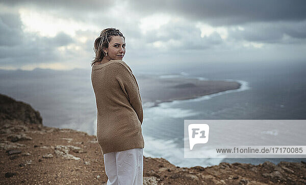 Frau steht auf einem Berg und starrt auf den Strand von Famara  Lanzarote  Spanien
