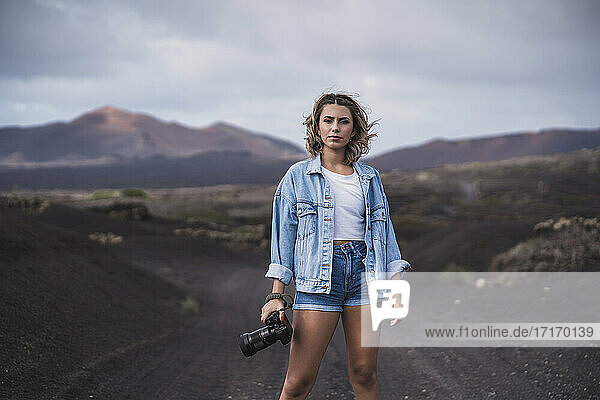 Junge Frau steht mit Kamera auf dem Fußweg am Vulkan El Cuervo  Lanzarote  Spanien