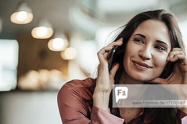 Lächelnde weibliche Fachkraft beim Telefonieren im Café