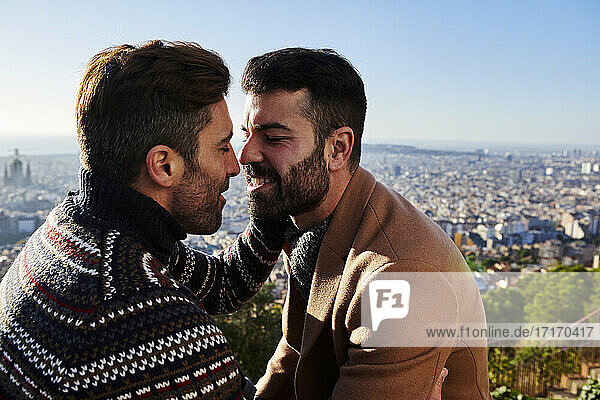 Gay men romancing while sitting against cityscape  Bunkers del Carmel  Barcelona  Spain