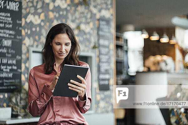 Smiling female freelancer working on digital tablet in cafe