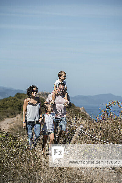 Family hiking at trail against blue sky