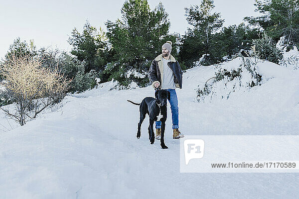 Junger Mann und Hund wandern im Winter im Schnee